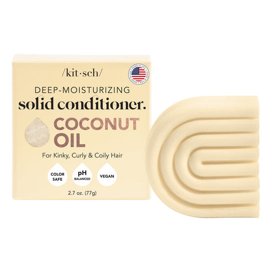 A solid conditioner bar lies next to its box labeled Kitsch Coconut Oil Deep Moisturizing Conditioner Bar, designed for kinky, curly, and coily hair. It assures users its color-safe, pH balanced, and vegan-friendly.