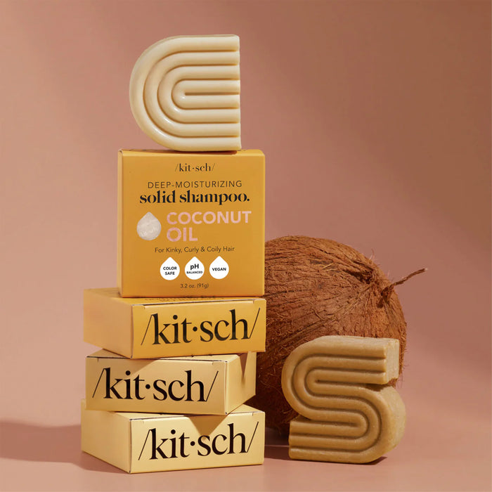 Kitschs Coconut Oil Deep Moisturizing Conditioner Bars are stacked in vibrant yellow boxes, adorned with coconuts and geometric designs. These vegan, cruelty-free, pH-balanced bars feature coconut oil and shea butter for deep moisturizing.