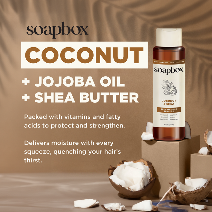 A bottle of Soapbox Coconut & Shea Deep Moisture Shampoo sits on brown blocks with cracked coconuts and a textured brown background, highlighting its moisturizing, hydrating, and strengthening benefits.