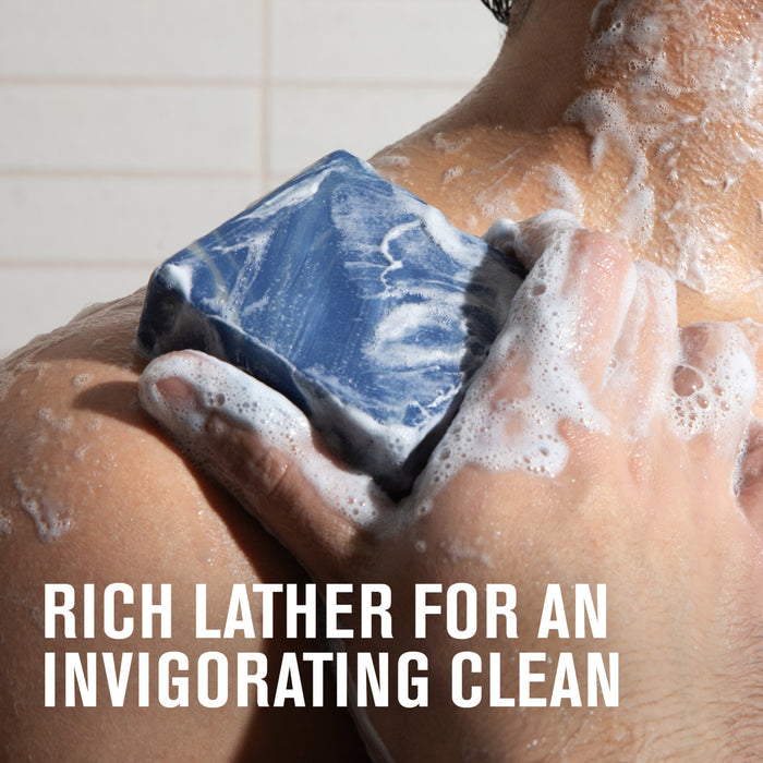 A person washing their shoulder with a blue and white Every Man Jack Cold Plunge Bar Soap, creating a rich lather. Text reads: Rich lather for an invigorating clean.