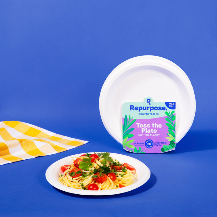 A white compostable dinner plate made from non-toxic sugarcane scraps holds spaghetti and cherry tomatoes on a yellow checkered cloth. Behind it, another plate with Repurpose packaging is set against a blue background.