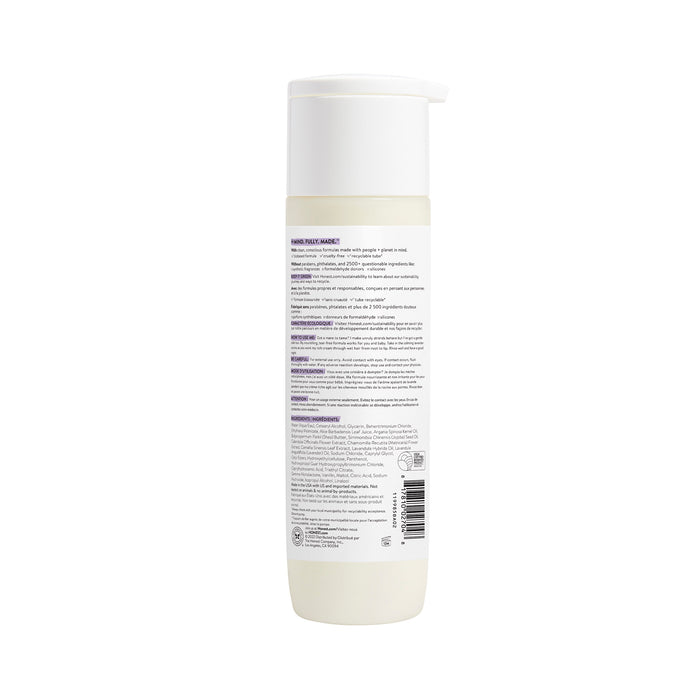 The Honest Companys sleek white cylindrical conditioner bottle with pump top and multilingual back label displays instructions, ingredients, and certifications. This silicone-free formula with Chamomile Extract offers an elegant look against a plain white background.