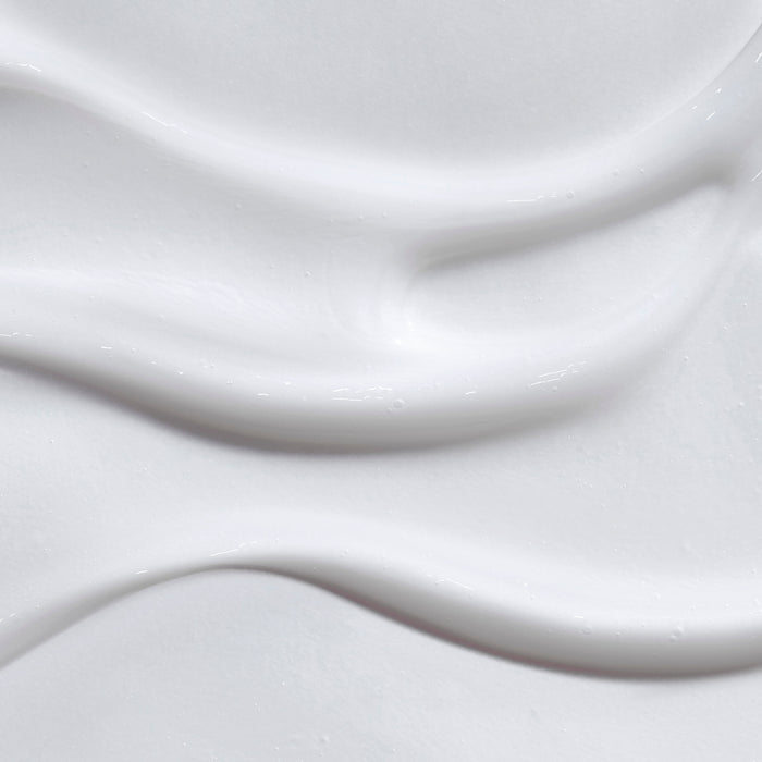 Close-up of The Honest Company Conditioner, a white, creamy substance with smooth, wavy textures. Infused with chamomile extract, it features gentle, flowing curves that create a soft, fluid appearance.