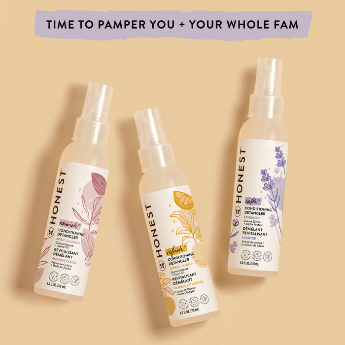 Against a beige background, three bottles of The Honest Companys Conditioning Detangler show off floral designs in purple, orange, and yellow. A banner above reads Time to pamper you + your whole fam, promising silky-smooth strands with its unique formula.