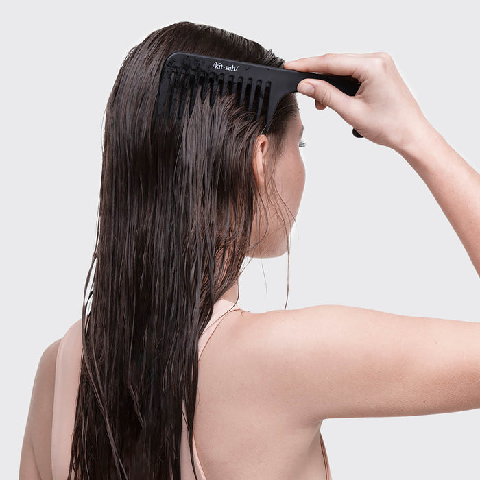 A person with long, damp hair uses the Kitsch Consciously Created Wide Tooth Comb to gently detangle, ensuring a smooth process with its no-slip texture.