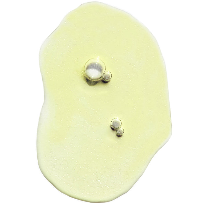 A translucent, pale yellow liquid with bubbles sits on a white background, resembling a glossy puddle—perfect for clean skincare routines or as an energizing Indie Lee CoQ10 Toner - Travel.