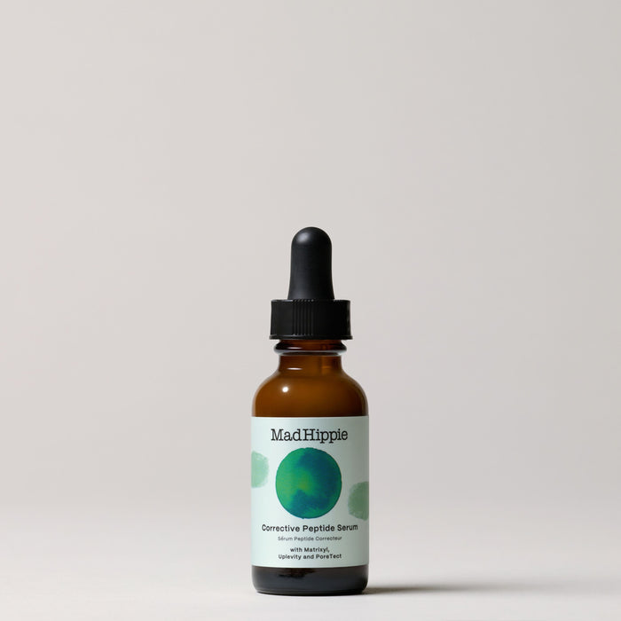 A brown dropper bottle of Mad Hippie Corrective Peptide Serum sits against a light grey background. The label displays a blue-green circular design and promises to effectively address wrinkles and sagging skin.