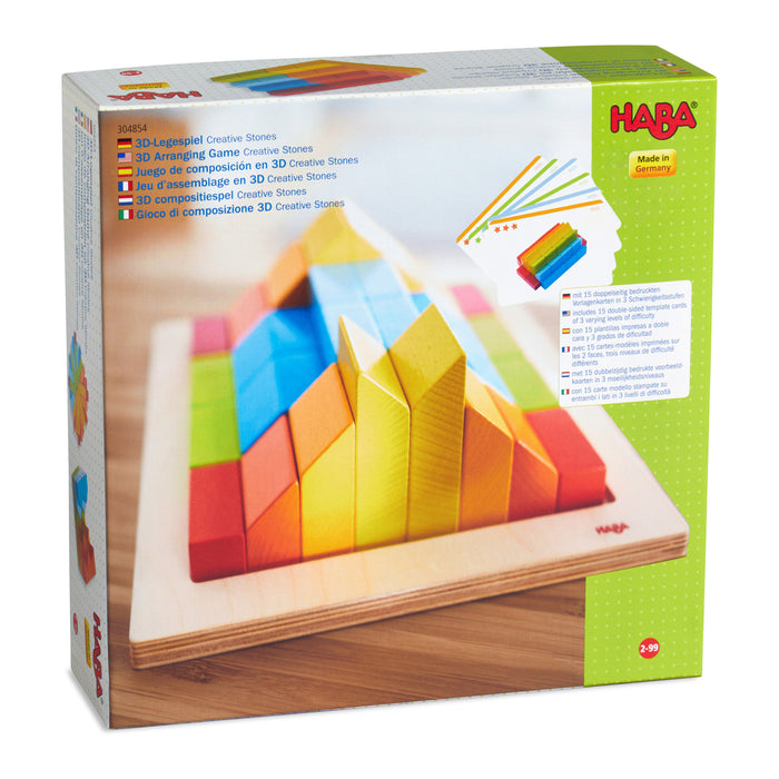 The HABA Creative Stones - 3D Wooden Arranging Blocks set features a colorful box with multicolored wooden blocks creatively arranged on a board. Ideal for ages 2 and up, this set offers endless fun and creativity.
