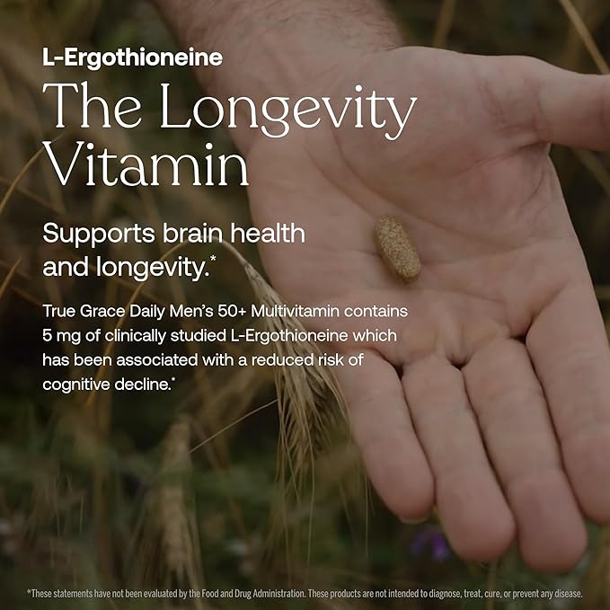 A hand holds a brown capsule outdoors above green grass. Overlaid text highlights L-Ergothioneine as The Longevity Vitamin for longevity and memory support, featured in True Grace Daily Men’s 50+ Multivitamin.