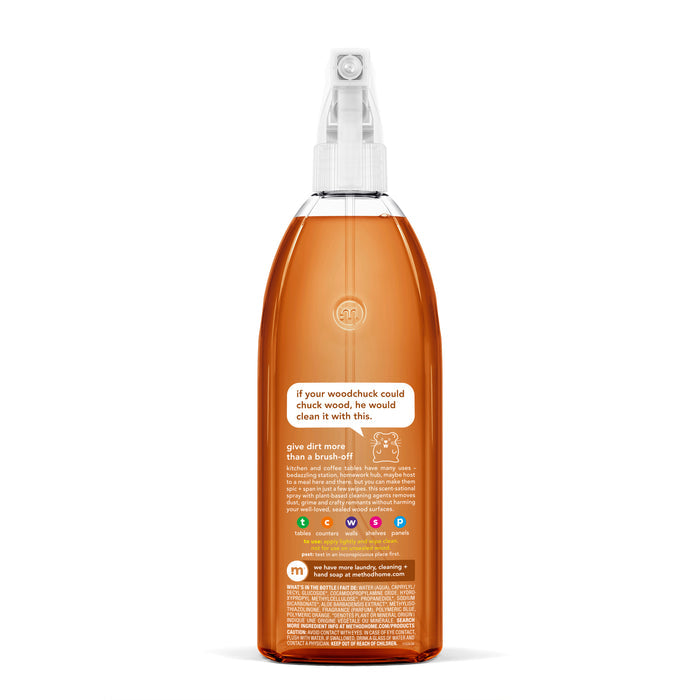 The clear spray bottle, crafted from recycled plastic, holds orange liquid topped with a white nozzle. The Method brand logo and a woodchuck-themed label with bottom icons symbolize its cruelty-free Daily Wood Cleaner assurance.