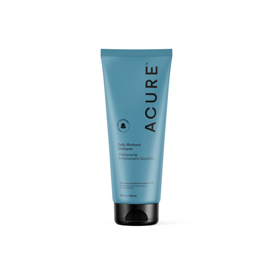 A blue tube of Acure Daily Workout Shampoo stands upright on a white background, featuring black text, a circular icon, and a black flip-top cap; perfect for daily hair washing.