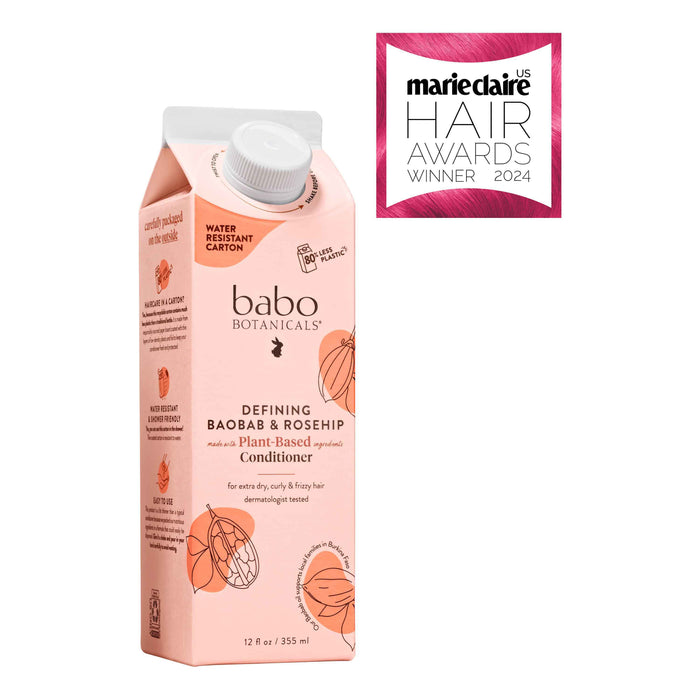 Carton of Babo Botanicals Defining Baobab &amp; Rosehip plant-based conditioner next to a Marie Claire US Hair Awards Winner 2024 badge. The carton is light pink with floral graphics.