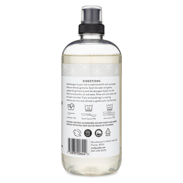 Mollys Suds Delicate Wash comes in a 473 ml clear plastic bottle with a black spray nozzle, perfect for delicate fabrics. The label includes usage instructions, garment icons, and safety warnings. Made with earth-derived ingredients.