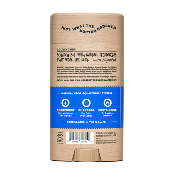 The back of a Dr. Squatch Deodorant stick with a blue label on a tan background showcases natural deodorizers like arrowroot, charcoal, and postbiotics. Just What The Doctor Ordered is at the top, while Made in the U.S.A. is noted at the bottom.