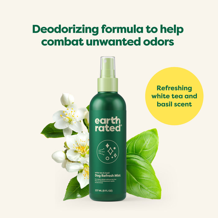 A green spray bottle labeled Earth Rated Deodorizing & Conditioning Refresh Mist for Dogs is surrounded by white tea flowers and basil leaves, providing a no-rinse solution with a refreshing white tea and basil scent to effectively combat unwanted odors.