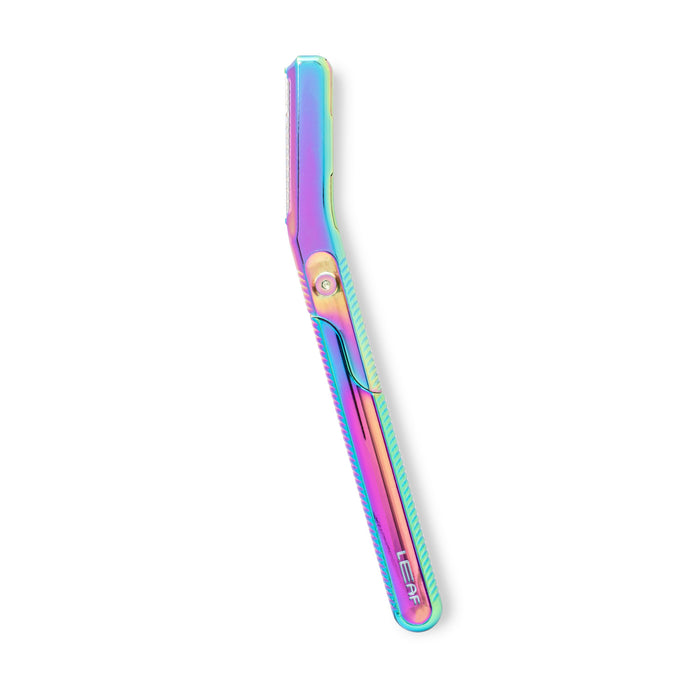 The Dermaplaner Kit by Leaf Shave features a sleek straight razor with an iridescent metallic finish reflecting purple, blue, green, and pink hues. Angled right against a white background, this eco-friendly tool offers a zero-waste approach to exfoliating skin.
