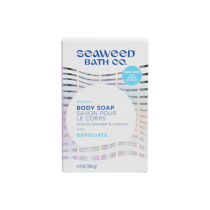 A white box of The Seaweed Bath Cos Detox Exfoliating Body Soap, labeled in English and French as detox and exfoliate, contains Atlantic seaweed and charcoal. It features a wavy silver pattern and weighs 3.75 oz (106 g).