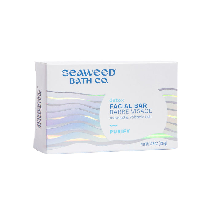 The Detox Purifying Facial Bar by The Seaweed Bath Co. comes in a white box featuring Purify in blue, combining seaweed and volcanic ash with charcoal powder. It weighs 3.75 oz (106 g), and the packaging dazzles with subtle holographic wave patterns.