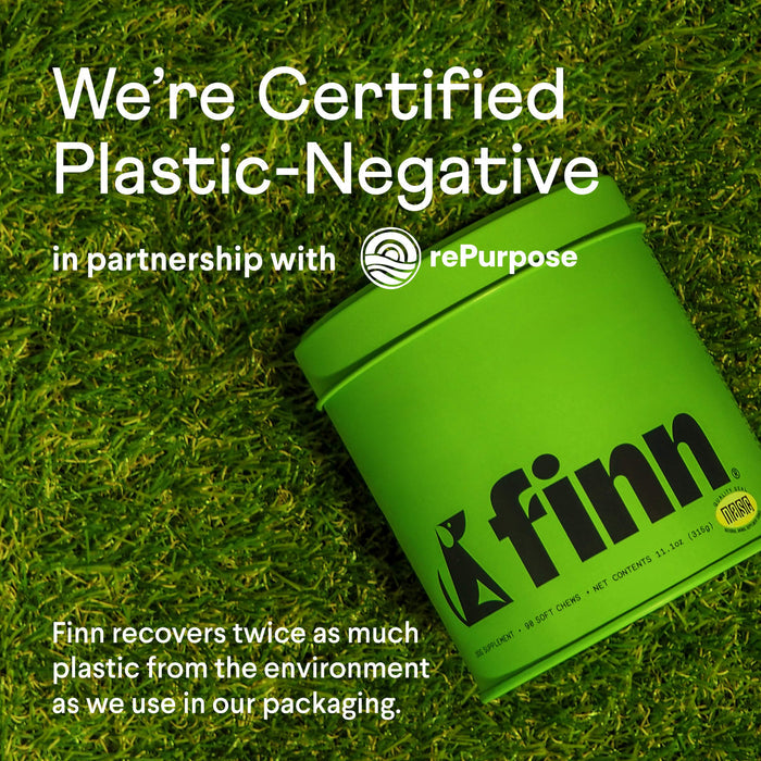 A green container with the Finn logo on grass says: We’re Certified Plastic-Negative with rePurpose. Finn recovers twice the plastic used in packaging, promoting healthy dog digestion with our Digestive Probiotics Supplement For Dogs.