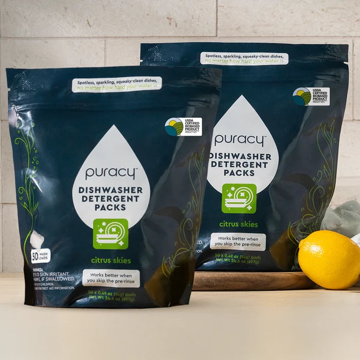 Two bags of Dishwasher Detergent Pods, citrus scent, on a counter with a lemon nearby.