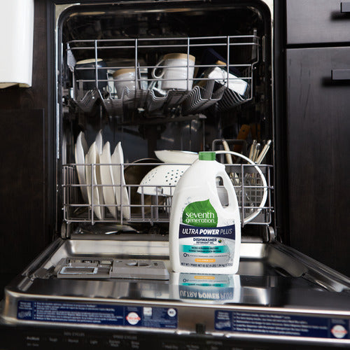 An open dishwasher filled with clean dishes, cups, and bowls has a large bottle of Seventh Generation Dishwasher Gel Power Plus on the open door in the foreground.