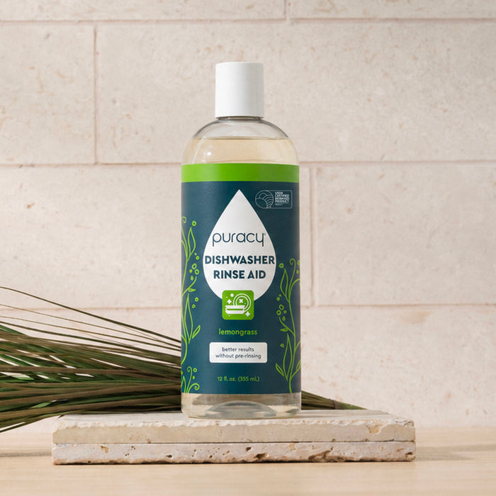 A bottle of Dishwasher Rinse Aid in lemongrass scent on a white tile surface.