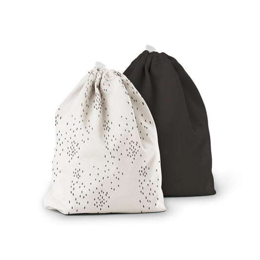 The Ditty Bag Duo Wet Bags by Esembly Baby are displayed. The left bag, made from recycled plastic, showcases small black dots on white, and the right one is solid black. Both bags stand upright against a plain white background.