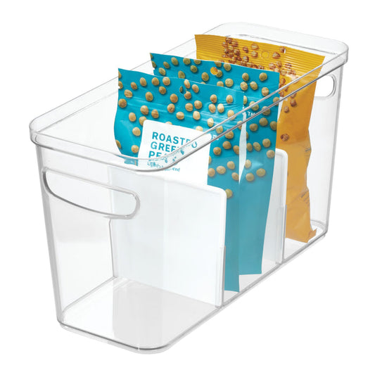 The iDesign Divided Organizer Bin with Handles, made from recycled BPA-free plastic, holds three snack bags upright. The bin has two turquoise bags with roasted peas and one yellow bag arranged in three compartments for neat kitchen storage.