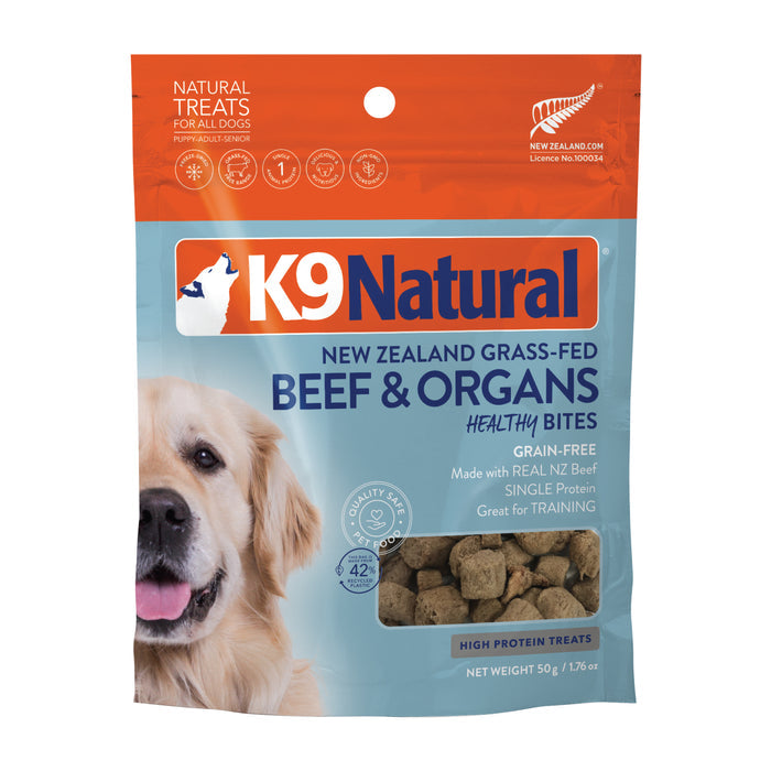 A package of K9 Natural Grain-Free Freeze-Dried Dog Treats is showcased with New Zealand grass-fed beef and organs. The front displays a happy dog, emphasizes high protein, single protein benefits, and highlights its grain-free nature.