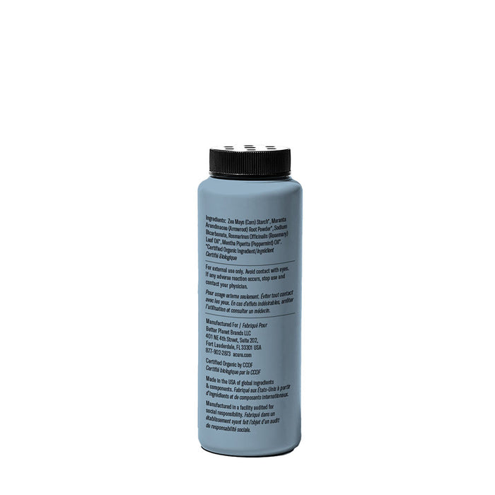 A tall, cylindrical plastic Acure Dry Shampoo bottle with a black cap is shown from the side, displaying its label with ingredients and instructions. This gray waterless shampoo absorbs hair oil, set against a white background.