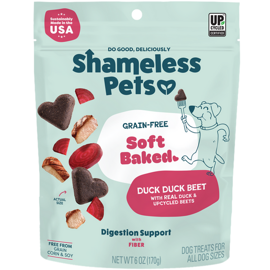 Shameless Pets Duck Duck Beet Soft-Baked Dog Treats come in a teal bag with heart and round-shaped treats, beets, and a cartoon dog holding a fork. These natural treats use upcycled ingredients and support healthy digestion.