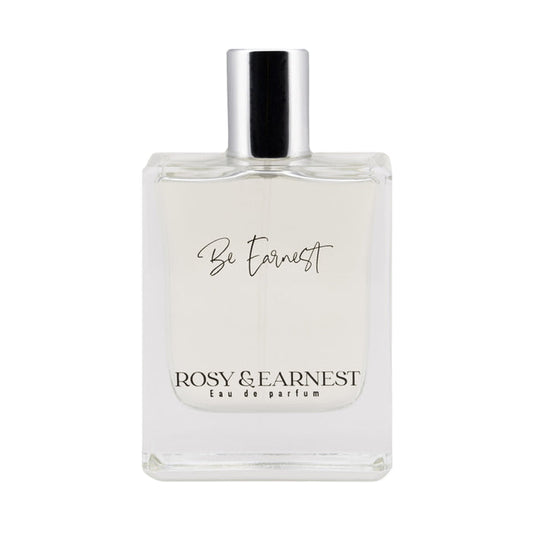 The Be Earnest perfume by Rosy & Earnest is a clear bottle capped in silver, labeled elegantly with its name. Below, its marked Eau de Parfum. This vegan scent is light and transparent with a subtle woody aroma.