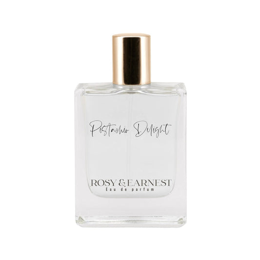 The Pistachio Delight by Rosy & Earnest is a cruelty-free gourmand Eau de Parfum in an elegant rectangular clear glass bottle with a gold cap, showcasing a minimalistic design and transparency.