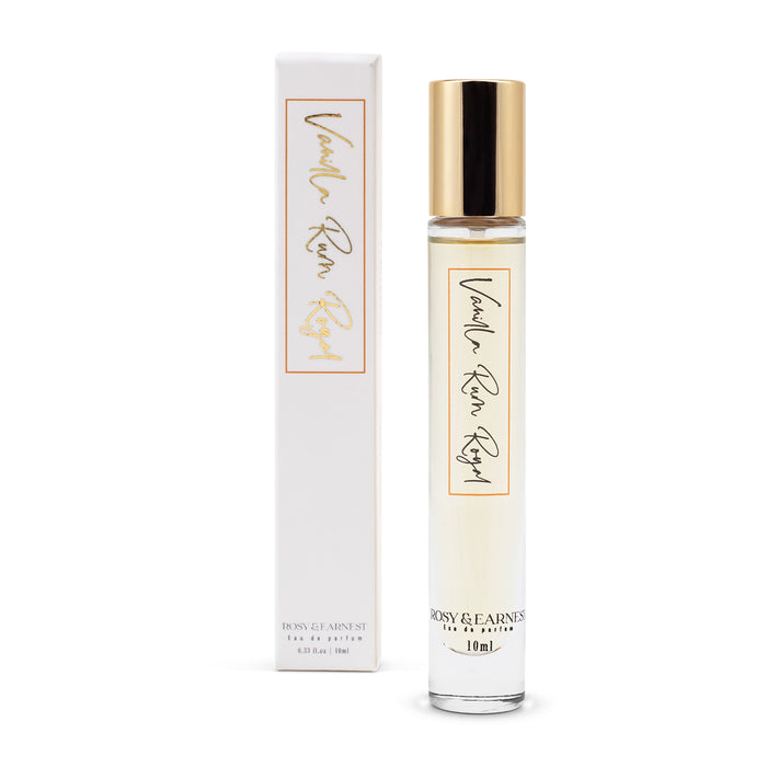 A 10 ml slender glass bottle of Rosy & Earnests Vanilla Rum Royal perfume, adorned with a gold cap, stands beside a matching white box. Both feature elegant script and the EWG VERIFIED™ mark, reflecting luxury.