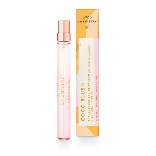 A slim, transparent bottle of Good Chemistrys Eau De Parfum Travel Spray, labeled Coco Blush, stands beside its orange box with floral accents. The vegan fragrance is detailed as a rollerball duo infused with essential oils.
