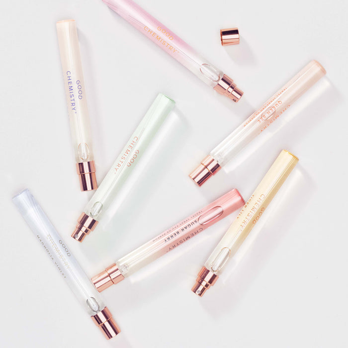 Nine Good Chemistry Eau De Parfum vials, each with pastel-colored liquid and a rose gold cap, labeled Cheerful Charmer, are scattered on a white background.