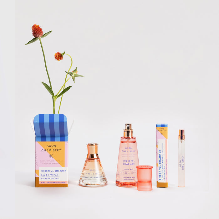Good Chemistrys Eau De Parfum Travel Spray is elegantly presented in various formats, such as travel sprays and roller tubes, featuring a vibrant red and orange flower with lush green leaves against a white background to add a natural touch.