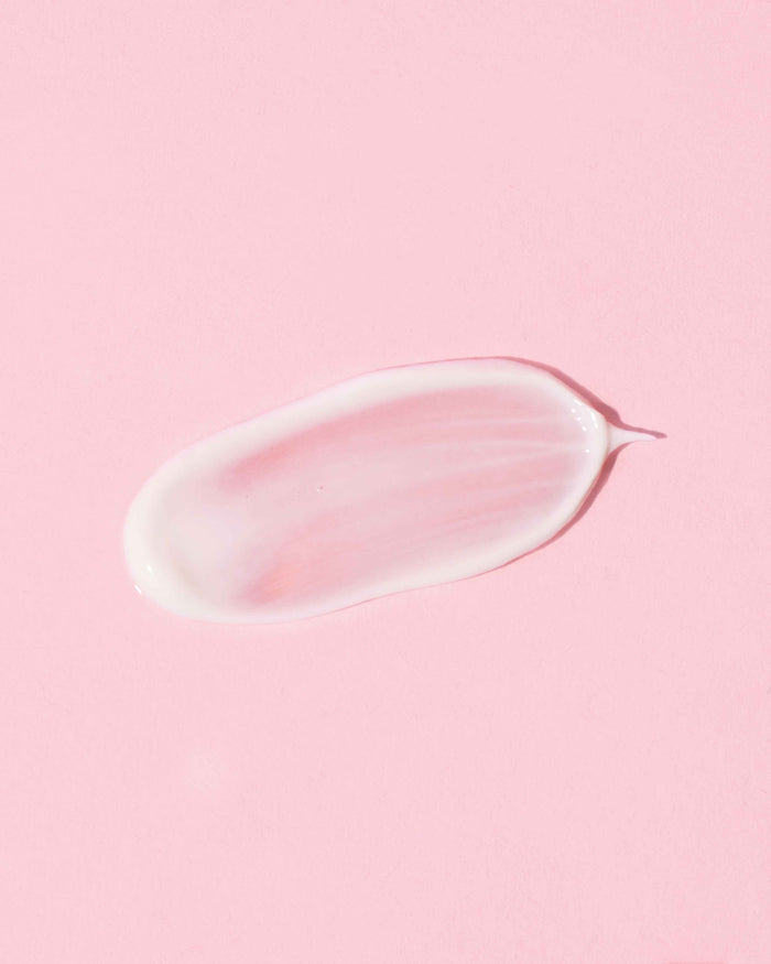 A smear of the creamy ECLIPSE Sheer Mineral Sunscreen SPF 30 by Earth Harbor, infused with mineral goodness, graces the pastel pink background.