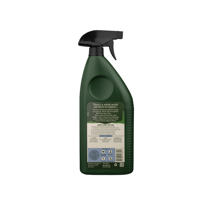 Back view of a Gear Hugger Eco Bike Wash bottle with a black nozzle. The label provides instructions and details on its non-toxic formula, ideal for bike cleaning. A message about exploring the world is featured alongside icons and barcodes, promoting environmental awareness.