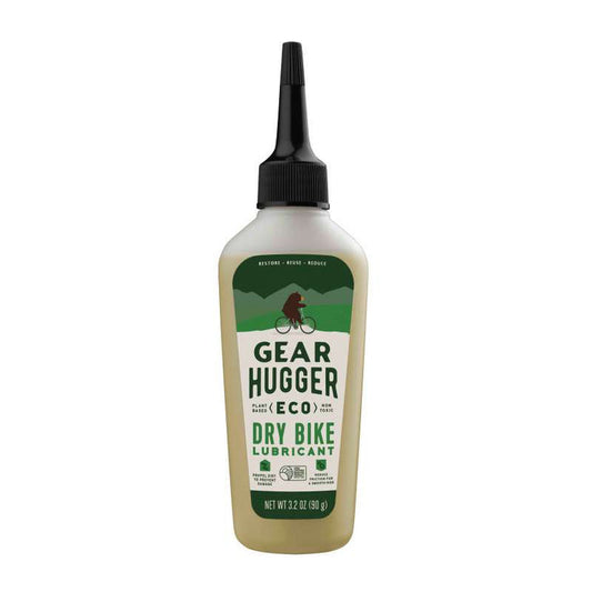 This non-toxic Gear Hugger Eco Dry Bike Lubricant comes in a beige bottle with a black nozzle and features a cyclist graphic. Its bio-based formula highlights Restore - Renew - Revive. Net Weight: 32 OZ (910g).