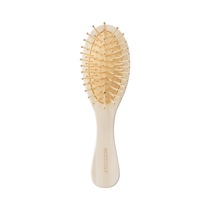 The EcoTools Eco Mini Shine Brush, crafted from 100% renewable bamboo in beige, features a curved handle and widely spaced bristles for gentle detangling. The handle displays the EcoTools logo, and the brush is elegantly showcased on a plain black background.