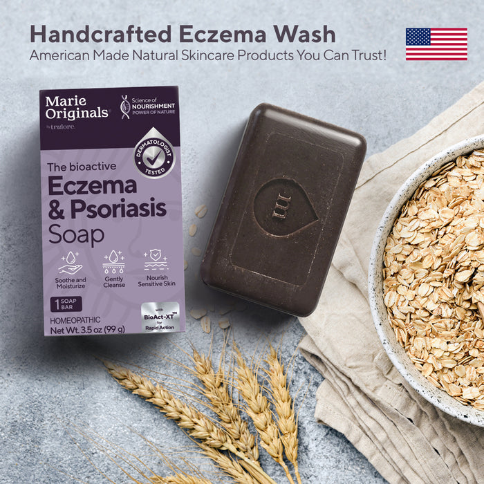 A bar of Marie Originals Eczema & Psoriasis Relief Soap rests on a light surface near oats. Text: “Handcrafted in the USA – Natural Bar Soap for Sensitive Skin from Marie Originals. Products You Can Trust!”.
