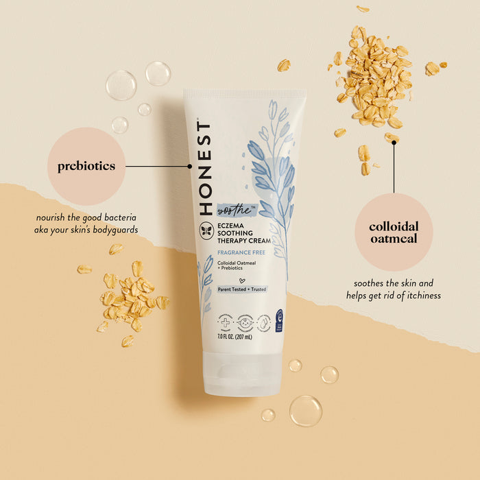 A tube of The Honest Company Eczema Relief Cream is on a beige background, ideal for eczema-prone skin. Scattered oats highlight prebiotics for nourishing skin bacteria and colloidal oatmeal for soothing and reducing itchiness, ensuring daily moisture.