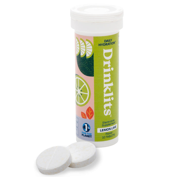 A cylindrical Drinklits container titled Electrolyte Hydration Tablets features a lemon-lime design, containing zero-sugar electrolyte tablets. Two white tablets are displayed in front. The label reads 10 Tablets and includes the 1% for the Planet logo.