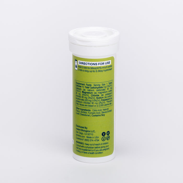 A cylindrical white container with a plastic lid features a green label for Drinklits Electrolyte Hydration Tablets, displaying directions and ingredients. It advises dissolving the tablets in water to release essential electrolytes, alongside distribution info and a barcode.