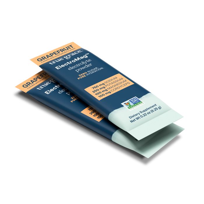 Image depicts two packets of True Graces ElectroMag™ in grapefruit flavor. The navy blue packs, accented in orange, detail sodium, potassium, magnesium, and chloride content. This essential electrolyte powder is perfect for staying refreshed and replenished.