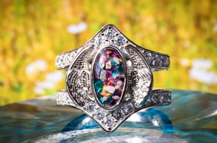 Sterling Silver Embraced Opal Angel Wings Ring, with turquoise and magenta crushed opal, sitting atop a glass surface. Sterling Silver Jewelry for Ash, Sterling Silver Ring, Sterling Silver Angel Wing, Angel Jewelry, Angel Jewlery for Ash, Ring for Remembrance, Memorial Jewelry