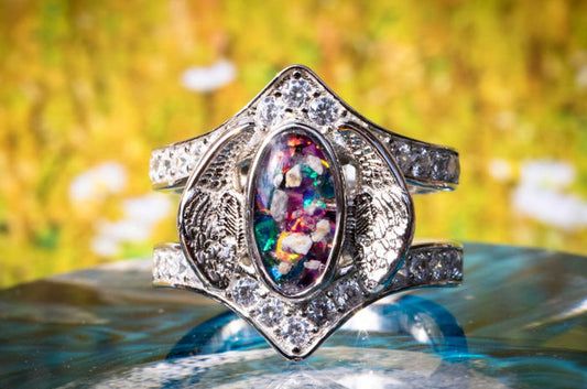 Sterling Silver Embraced Opal Angel Wings Ring, with turquoise and magenta crushed opal, sitting atop a glass surface. Sterling Silver Jewelry for Ash, Sterling Silver Ring, Sterling Silver Angel Wing, Angel Jewelry, Angel Jewlery for Ash, Ring for Remembrance, Memorial Jewelry