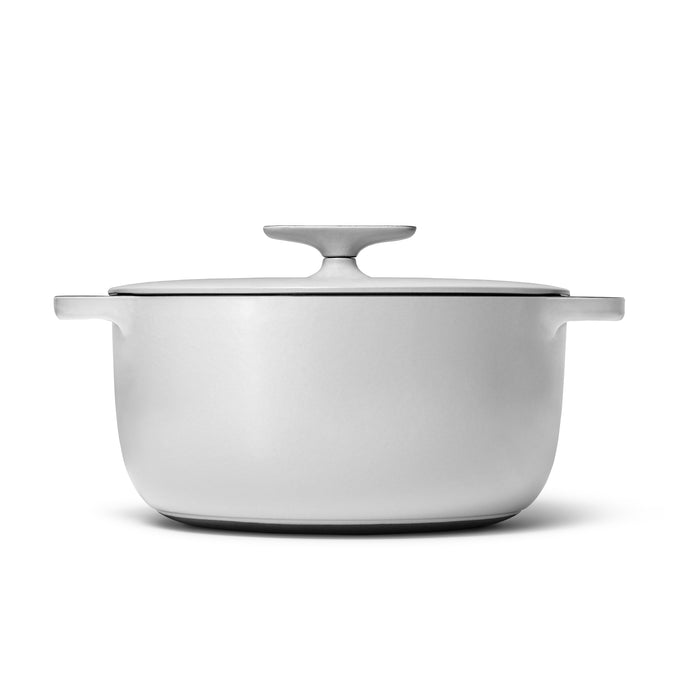 The Caraway Cast Iron Dutch Oven with Flat Lid, 6.5 qt is a non-toxic, white, round pot with side handles and a simple, modern design. It offers superior heat retention and is pictured against a white backdrop.