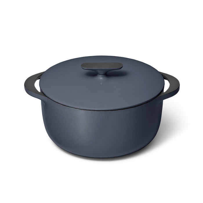 A matte dark gray Caraway Cast Iron Dutch Oven with Flat Lid, 6.5 qt, is shown on a white background. It has two handles and a stylish, slightly rounded shape. The non-toxic design features a simple handle on the lid for superior heat retention.